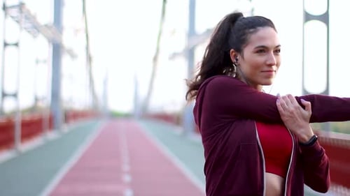Woman Stretching Arms on Urban Bridge