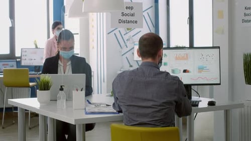 Employees in Masks Working in a Socially Distanced Office