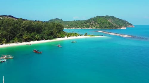 Paradise bay with calm clear water of turquoise lagoon and anchored boats near exotic beach under pa