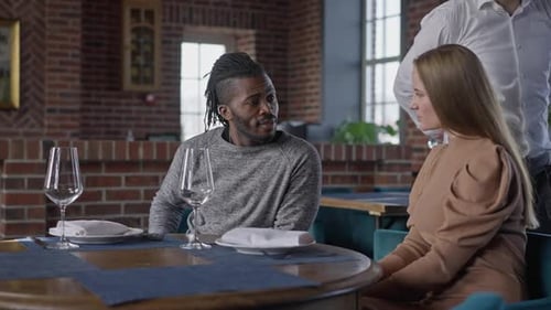 Couple Talking at Restaurant with Waiter Serving