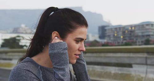 Woman Puts in Earbuds Before Outdoor Workout