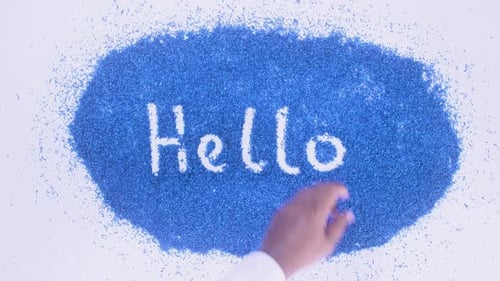 Hand Writing 'Hello' on Blue Shredded Paper