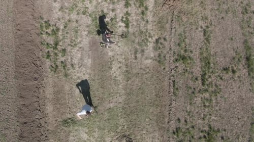 Top-Luftaufnahme von Männern, die am sonnigen Frühlingstag Gras schneiden und harken