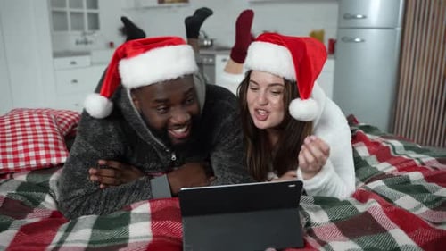 Couple in Santa Hats Watching Tablet at Christmas