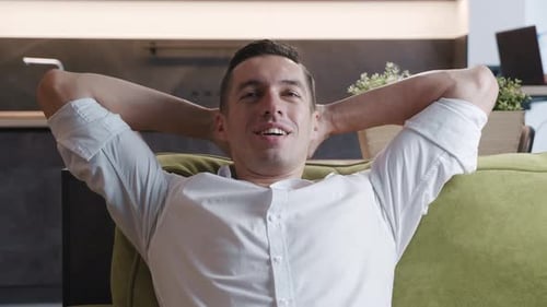 Calm Relaxed Young Man Resting on Cozy Sofa at Home. Happy Businessman Breathing Fresh Air Lounge on