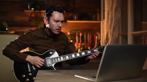 Man Plays Electric Guitar with Laptop at Home