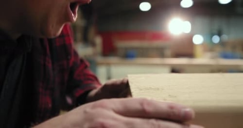 Man Blowing Sawdust off Piece of Wood