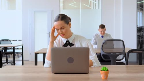 Stressed Woman Massaging Temples at Office Desk