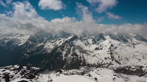 Air Flight Through Mountain Clouds Over Beautiful Snowcapped Peaks of Mountains and Glaciers