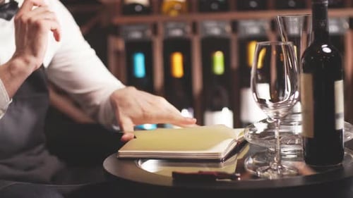 Man writes in notebook with wine and glasses