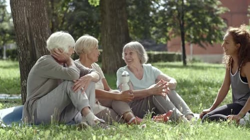 Senior Women Chatting With Yoga Instructor in Park