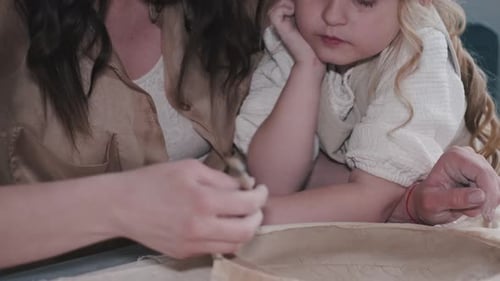 Child and Adult Making Pottery Together Indoors