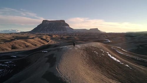 Following man walking in the desert leaving footprints
