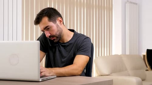Man Works on Laptop and Talks on Phone
