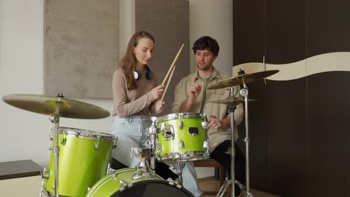 Lady suit des cours de batterie avec un professeur et apprend les bases