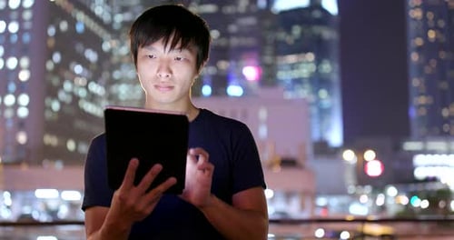 Young Adult Using Tablet at Night in City