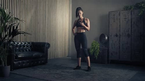 Woman With Smartphone Stands in Gym After Workout