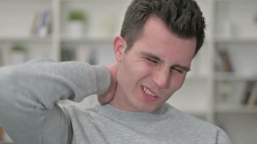 Young Man Rubbing Neck in Discomfort