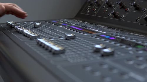 Man Works on a Professional Electronic Audio Mixer. A Control Panel for Tuning Sound Channels