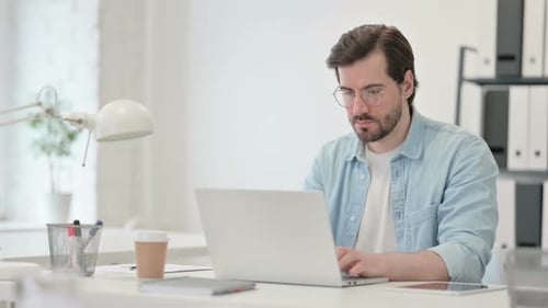 Young Man Working on Laptop in Office