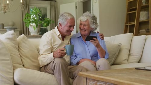 Senior Couple Enjoying Phone Together on Couch