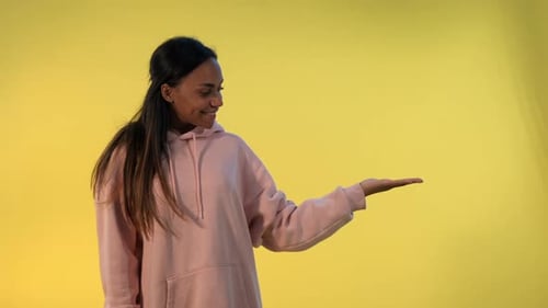 Smiling Woman Presenting on Yellow Background