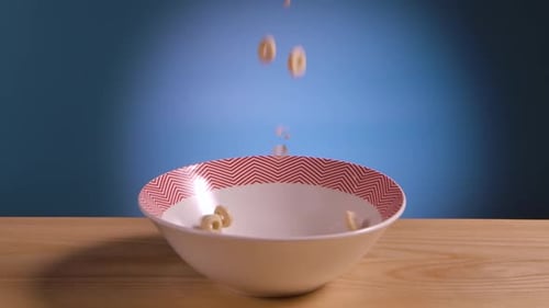 Breakfast Cereal in Form of Corn Rings Fall and Fill Bowl on Table