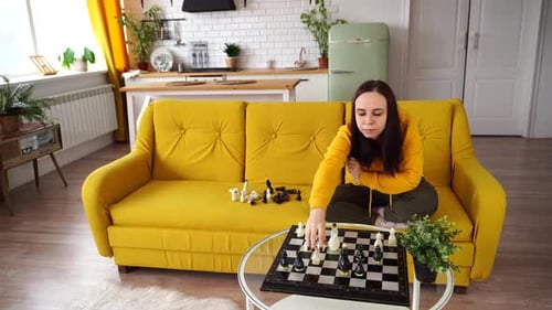 Woman Playing Chess on Yellow Couch Indoors
