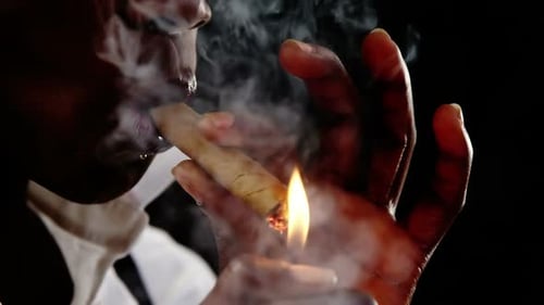 Androgynous man lighting a cigar