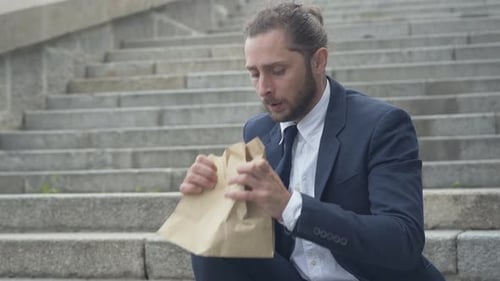 Man Breathes into Paper Bag on Urban Steps