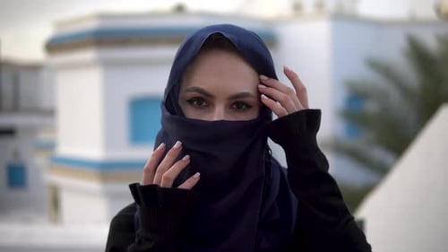 Junge Frau in arabischer Burka, Eine Frau schaut in die Kamera und richtet einen Schal gerade