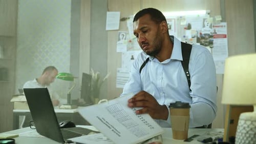 Focused Detective Reviews Files in Urban Police Office