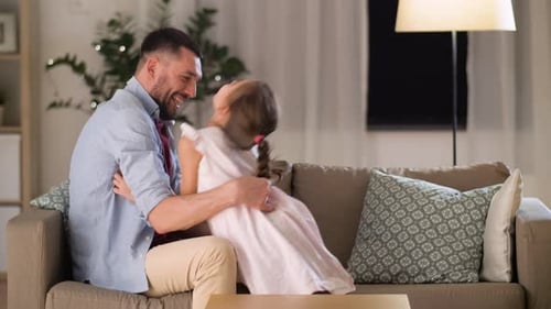 Happy Father Tickling Laughing Daughter on Sofa