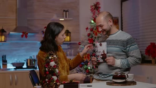 Couple Reading Christmas Cards in Kitchen at Night