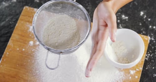 Flour Being Sifted onto Wooden Board for Baking