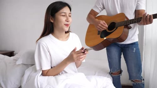 Woman Enjoys Guitar Music in Bed