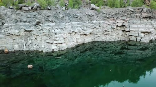 Person Hiking on Cliff Above a Still Lake