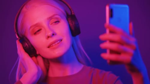 Woman Listening to Music with Headphones in Neon Light