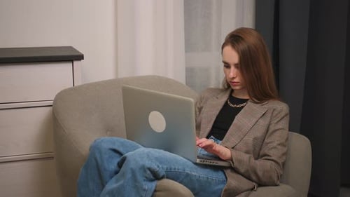 Woman Using Laptop While Sitting in Armchair