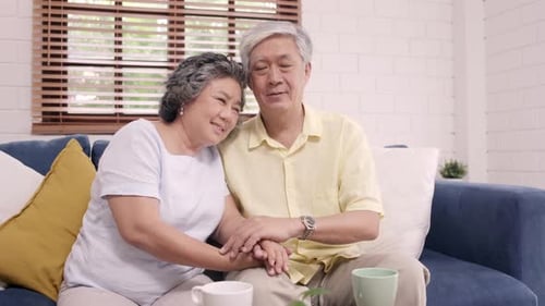 Senior Couple Holding Hands and Smiling at Home