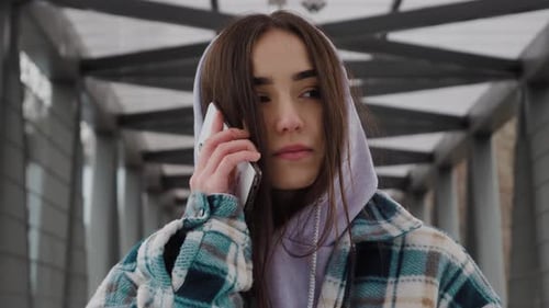 Serious Young Woman Talking on Phone Outdoors