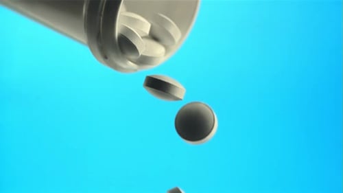 White Pills Falling from a Plastic Bottle