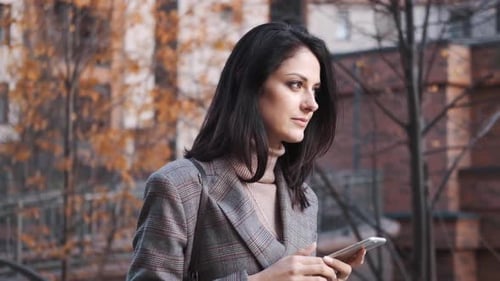 Smiling Woman Uses Smartphone in City Setting