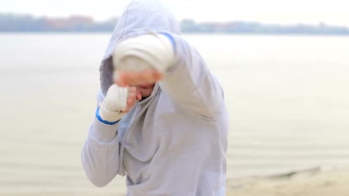 Man Training, Boxing, and Punching Outdoors