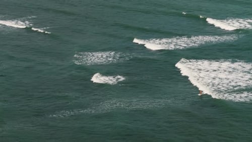 Aerial view of surfer rides in ocean