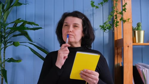Woman Thinks and Holds a Notebook