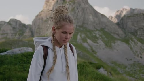 Peaceful travel woman with dreadlocks and backpack walking through the national park