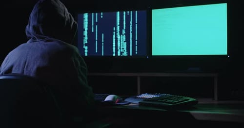Pirate informatique assis dans une pièce noire piratant des systèmes de sécurité