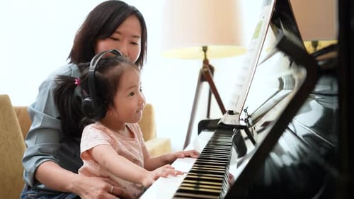 Adult and Child Playing Piano Together Indoors