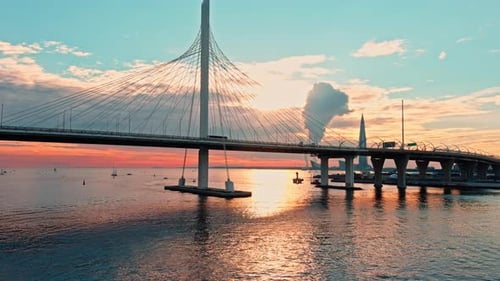 Aerial Footage of Cablestayed Bridge at Sunset Car Traffic on the Highway Over Water Magic